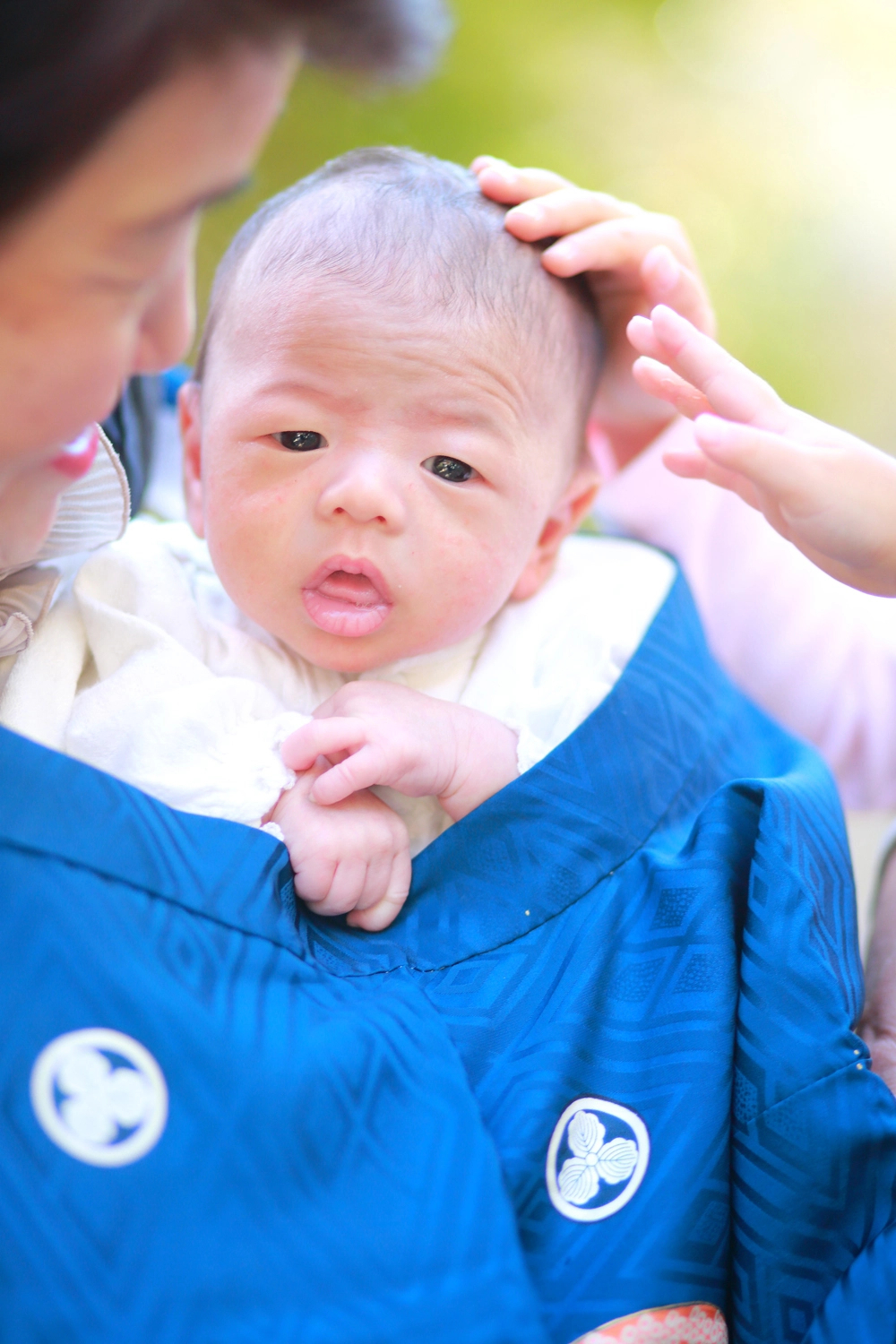 お宮参りで赤ちゃんにそっと手を添える家族